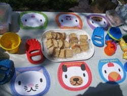 cute placemats on white table cover, mini sandwiches, sand toys, 3 balloons not pictured