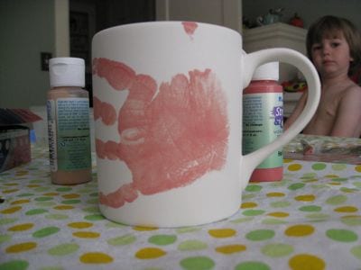 handprint on painted mug Julian looks on as Holden hand prints the mug