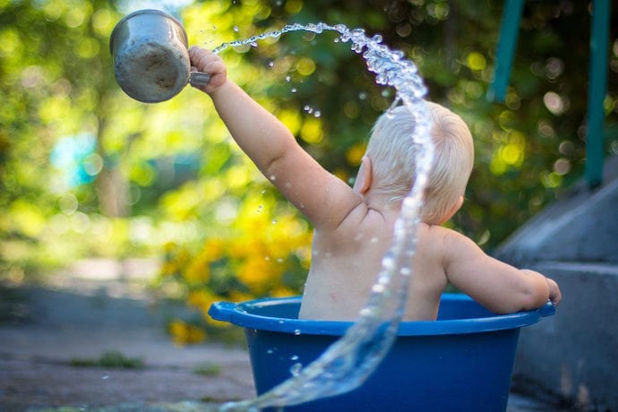 Baby or toddler playing with water in a bucket